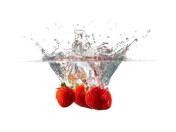 Three Strawberries Falling in Water Splash stock photo