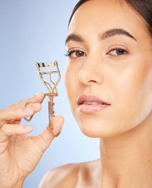 istock Face, beauty and woman with eyelash curler in studio isolated on a blue background. Portrait, skincare and makeup cosmetics of female model with metal tool or product to curl eyelashes for aesthetics 1468197607