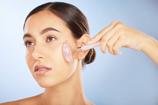 Woman, face or rose quartz roller for skincare grooming on blue background gradient for collagen treatment, wrinkles or lymph fluid wellness. Zoom, glowing or beauty model with facial stone massage rodillo de mujer, cara o cuarzo rosa para el cuidado de la piel sobre degradado de fondo azul para el tratamiento del colágeno, las arrugas o el bienestar del líquido linfático. zoom, modelo brillante o de belleza con masaje facial con piedras