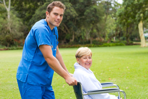 male nurse pushing a senior patient on wheelchair outdoors