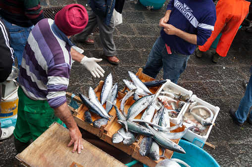 Horizontal high angle view of a fish vendor promoting its merchandise to potential customers in La Pescheria, the popular fish market, Catania, Sicily