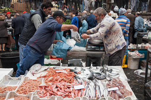 Horizontal shot of the fishes, fish vendors and general atmosphere of La Pescheria, the popular fish market, Catania, Sicily