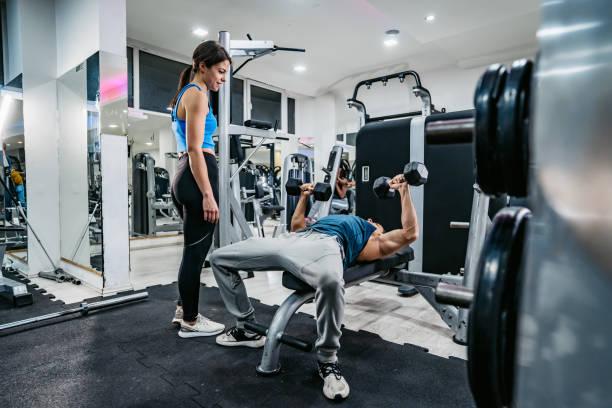 istock Young Female Trainer Helping Young Man Exercise In The Gym 1468204876