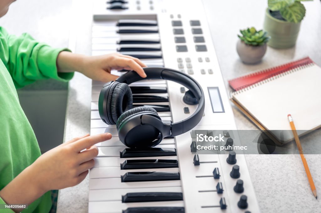 Close-up, black headphones in the hands of a child, music concept. Close-up, black headphones in the hands of a child on the background of the piano. Child Stock Photo