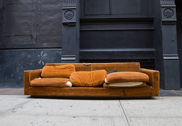 Orange couch on the street in Soho Old worn out 70's style orange sofa lingers on Soho NYC sidewalk just waiting for a drunken rock star to vomit on it. Includes clipping path. dirty old couch stock pictures, royalty-free photos & images