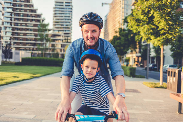 istock Small boy enjoying at the park with his father while learning to ride a bicycle. Smiling father teaching his son to ride bicycle in nature. 1468208824