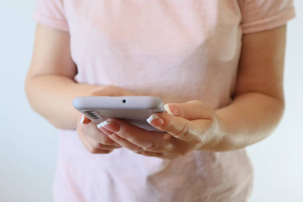 istock Woman hand using smartphone on light background. Woman using a Phone, close up view. 1468209376