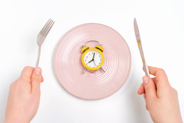 istock Female hands holding a fork and and knife next to an empty plate on a white background close-up top view. 1468218819