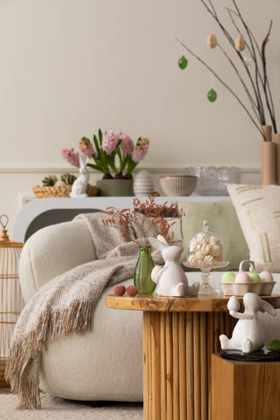 istock Warm and cozy composition of easter living room interior with coffee table, white sofa, colorful easter eggs, easter bunny, hyacinth, vase with branch and personal accessories. Home decor. Template. 1468218864