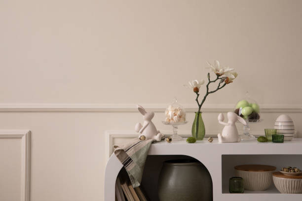 istock Minimalist composition of easter living room interior with copy space, easter bunny sculpture, easter eggs, vase with magnolia, wall with stucco and personal accessories. Home decor. Template. 1468219124