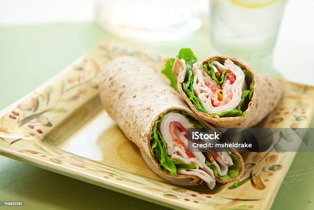 Turkey wrap with lettuce and tomatoes on a square plate healthy turkey wrap sandwich with lettuce, tomato, onion and peppers Wrap Sandwich Stock Photo