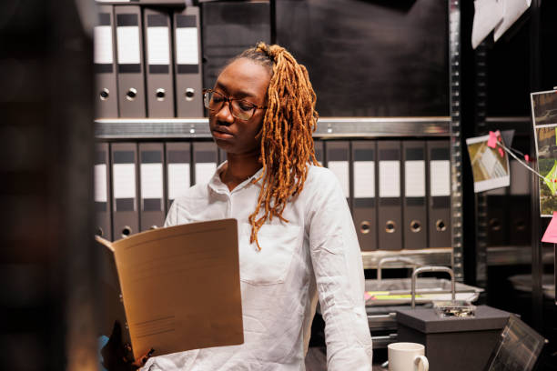 istock Policewoman standing near crime case folders shelf, reading report 1468224882