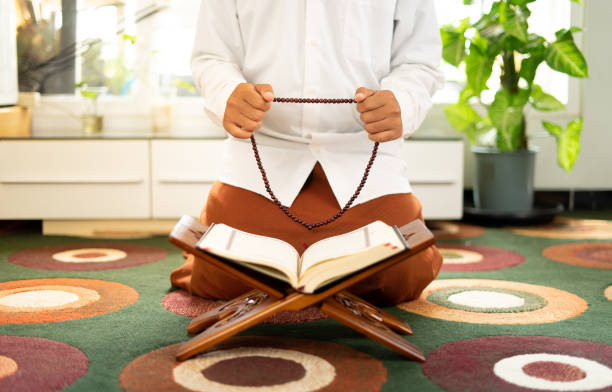 istock Man holding rosary while reading the Quran book 1468224983