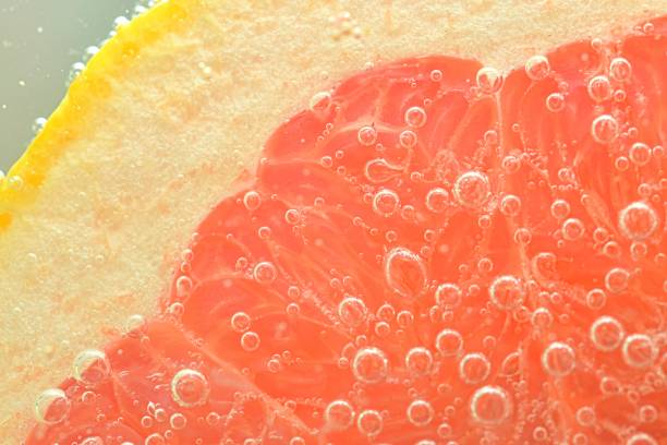 istock Close-up of fresh grapefruit slice on white background. Slice of red grapefruit in sparkling water on white background, close-up. Horizontal image 1468225080