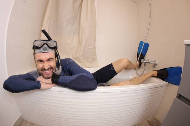 Humorous man snorkeling in the bathtub stock photo