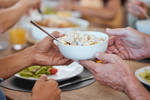 Lunch, family celebration and hands with potato salad, party food and group eating at the dining room table. Nutrition, healthy food and friends hosting a home dinner with a salad for health