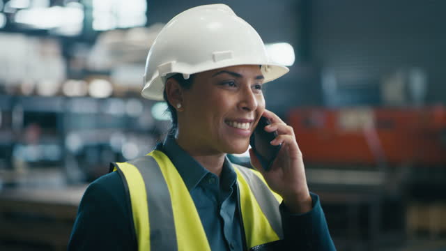 Woman, walking or phone call in factory warehouse, industrial plant or engineering workshop for logistics management. Smile, happy or talking manufacturing manager on mobile technology leadership