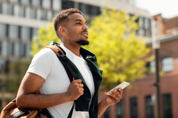 istock Handsome african american college guy using smartphone outdoors, walking in urban area after classes 1468231257