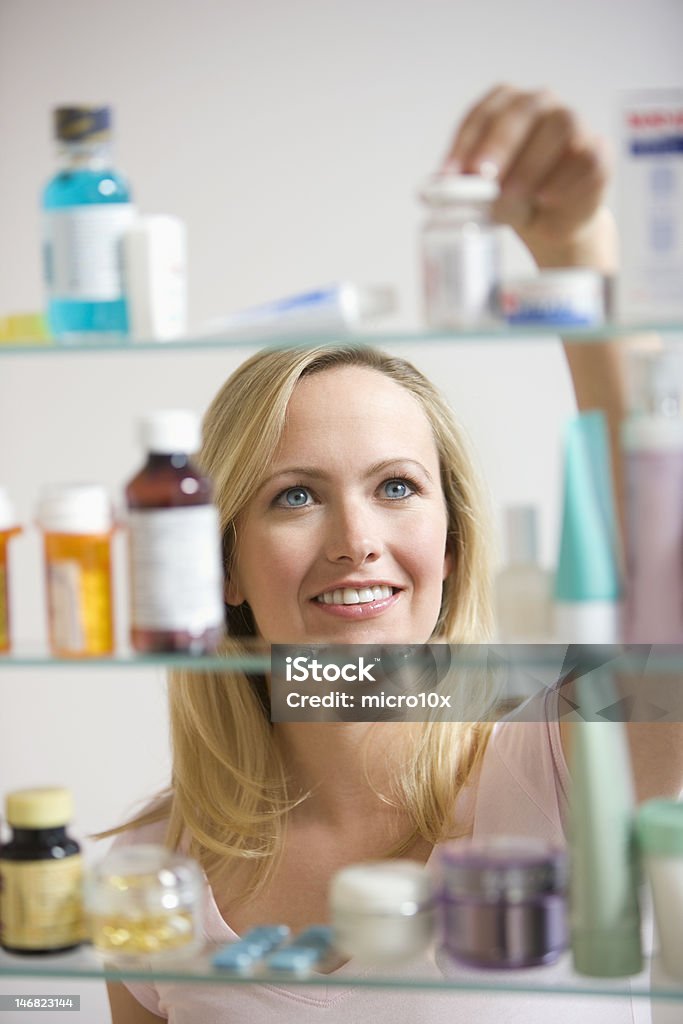 Женщина, глядя в Домашняя аптечка - Стоковые фото Домашняя аптечка роялти-фри