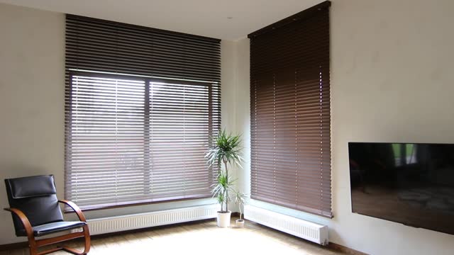 Wooden blinds closing down on large windows in the interior.