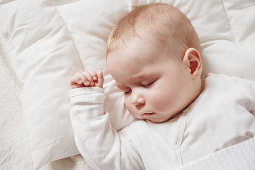 Adorable baby sleeping at night. Little girl in pajama taking a nap in room with toy.