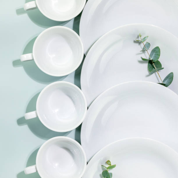 istock Empty white dishes and cups with eucalyptus twigs on blue background 1468235367
