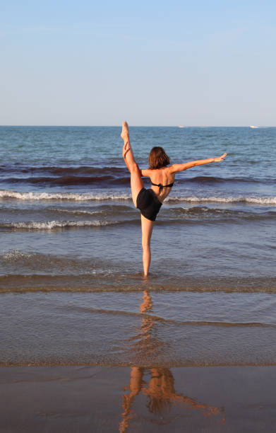 ragazza snella schiena contro schiena mentre fa esercizi di meditazione yoga e fa il simbolo om - only teenage girls teenager adolescence sea foto e immagini stock