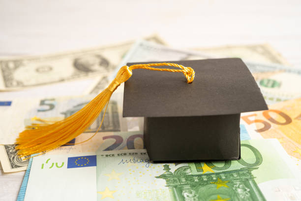 istock Graduation gap hat on Euro and US dollar banknotes money, Education study fee learning teach concept. 1468237824