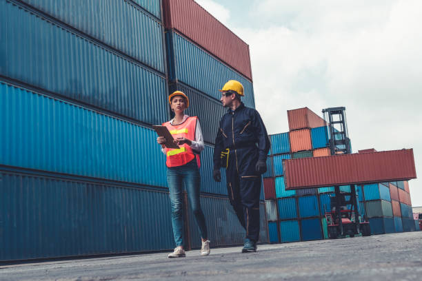 istock Industrial worker works with co-worker at overseas shipping container yard . Logistics supply chain management and international goods export concept . 1468239951