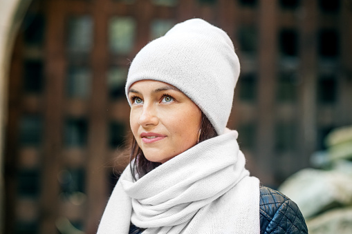 portrait of young woman in the park. Millennial woman in a warm hat and scarf outside.