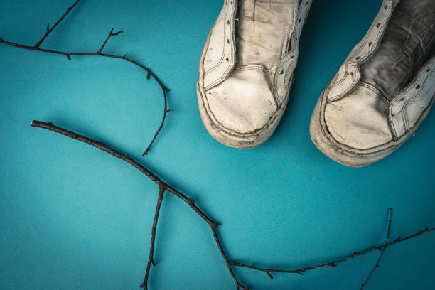 old battered women's sneakers without laces on a blue background. view from above. worn sneakers. High quality photo