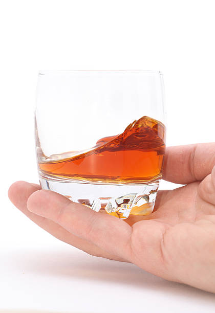istock glass of brandy holding by hand isolated on white 146824203