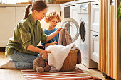 Son helping mom to load washing machine