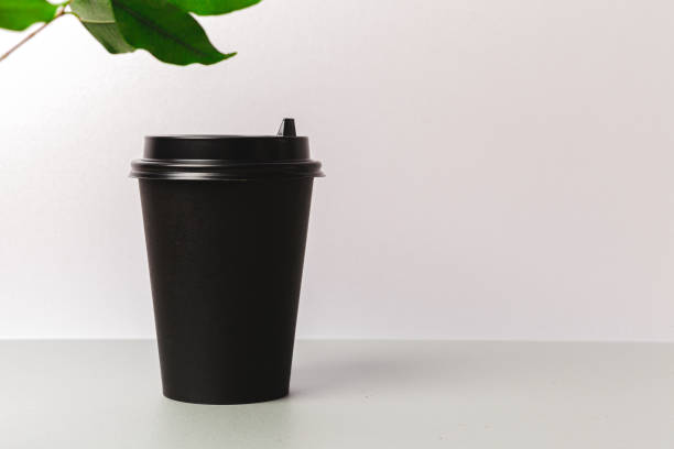 istock Disposable paper coffee cup and green leaf 1468243538
