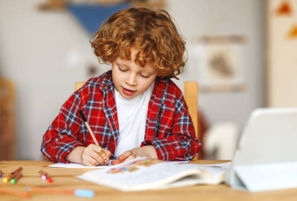 istock Smiling cute ginger child school boy studying online on tablet at home 1468243586