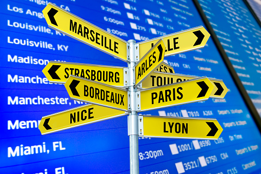 Road signs with travel locations in France in an airport arrival departure board