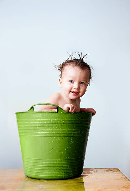 Baby bathing in green tub smiling