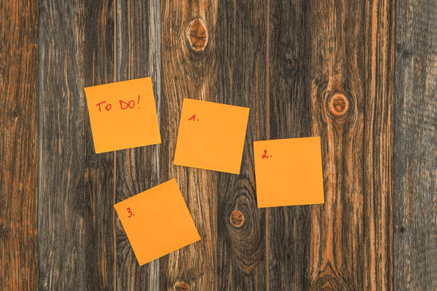 Sticky notes with a to do ljist and empty sticky notes on a brown wooden background.