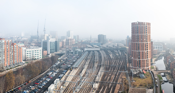 Leeds, UK - February 14, 2023.  An aerial panoramic view of Leeds cityscape skyline with railway station and tracks clouded in fog and mist reducing visibility