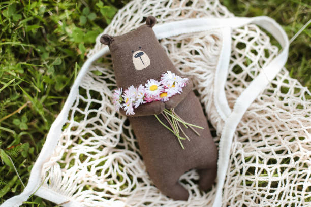 Eco-friendly cute handmade toy bear on grass at sunny summer day.