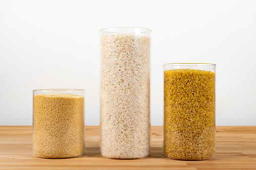 Glass storage jars full of couscous, rice and bulgur on a table