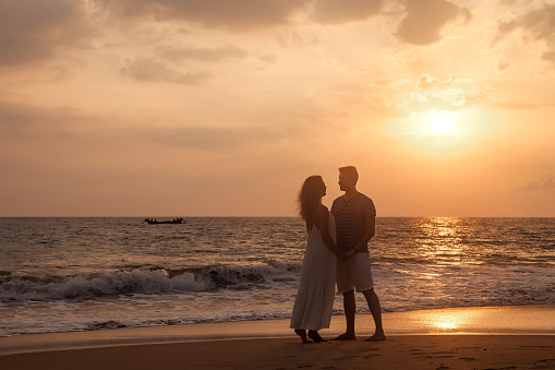 heterosexual couple hugging at sunset