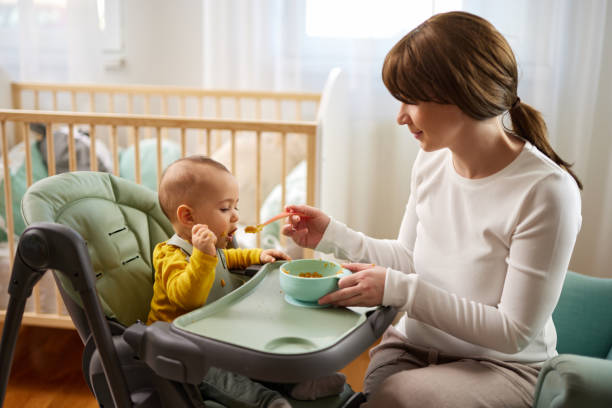 istock Mother spoon feeding her baby son at home 1468256538