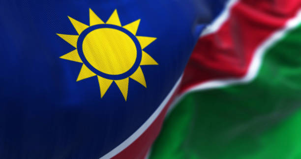 Close-up view of the Namibia national flag waving Close-up view of the Namibia national flag waving. Blue stripes, yellow sun, red, white stripes, green. Ovambo color. 3d illustration render. Selective focus. Close-up. Textured fabric background flag of namibia stock pictures, royalty-free photos & images