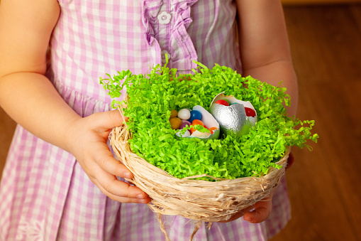 Little girl holding basket with colored eggs. Easter concept