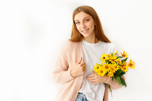 On white background, there is a portrait of a woman who is holding spring flowers and appears to be very happy
