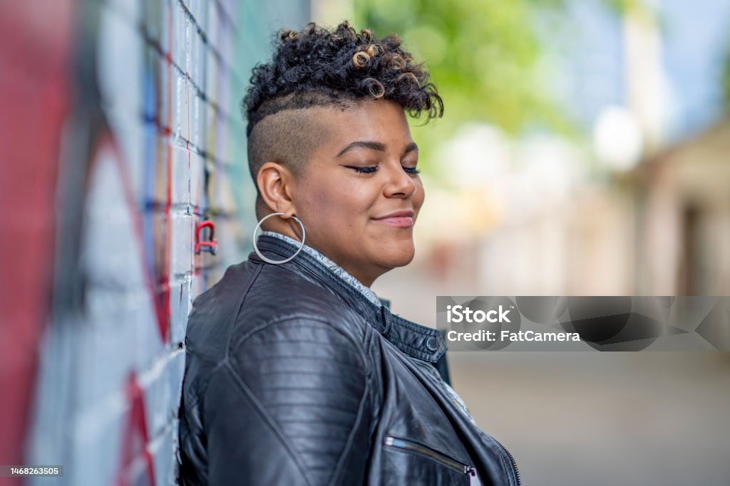 Portrait of a Yung Woman A young woman of African American decent, poses for a portrait while enjoying the outdoors.  She is dressed in a trendy leather jacket and smiling as she explores the downtown core. Lesbian Stock Photo