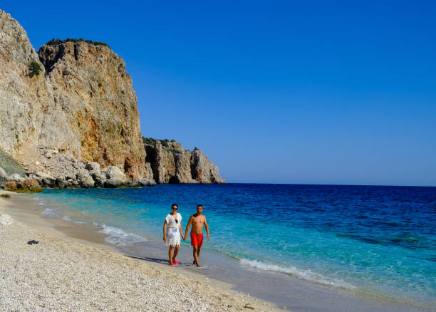Coulple walking on the beach and rocky mountains behind them in Suluada Antalya