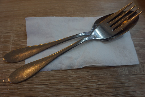 Fork with spoon and tissue paper on a wooden table in a cafe.