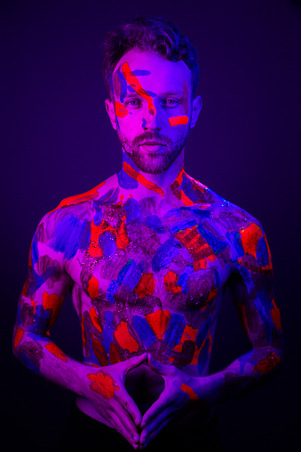Fashion portrait of a man with ultraviolet paint on his body and neon light in cyberpunk style.